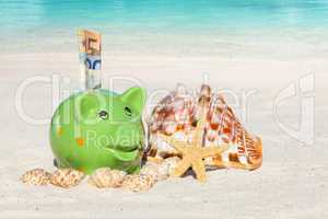 Grünes Sparschwein mit Geldscheinen am Sandstrand