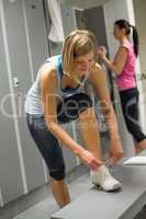 woman tying shoelaces in locker room
