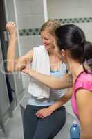 woman checking friend's muscles at changing room