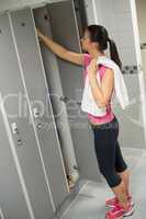 woman opening locker at gym