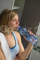 woman drinking water in gym's locker room
