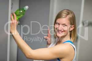 woman putting bottle in locker at healthclub