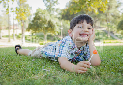 Young Boy Enjoying His Lollipop Outdoors Laying on Grass