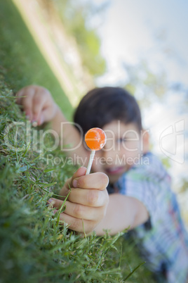 Young Boy Enjoying His Lollipop Outdoors Laying on Grass