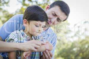 Loving Father Puts Bandage on Elbow of Young Son