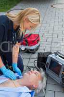 Paramedic examining unconscious elderly man