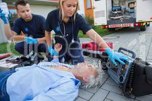 Paramedics checking pulse of unconscious man