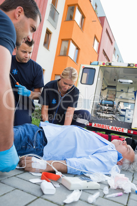 Emergency team examining injured patient on street