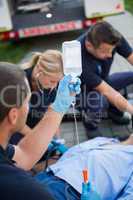 Paramedic team preparing drip for injured patient