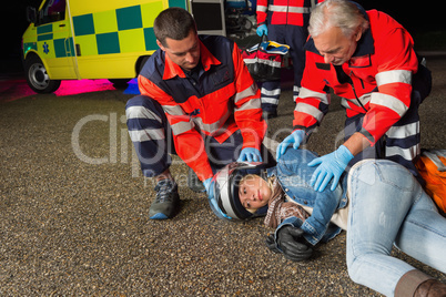Paramedics helping motorbike driver lying on road