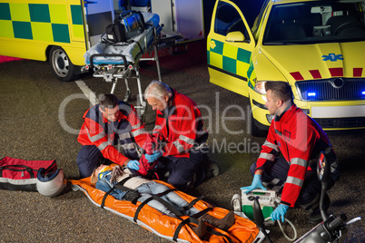 Paramedics helping motorbike driver on stretcher