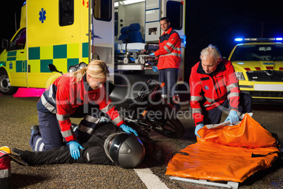 Emergency team assisting injured motorbike driver