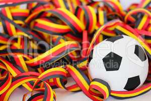 ein Fußball und Luftschlangen in schwarz, rot, gelb