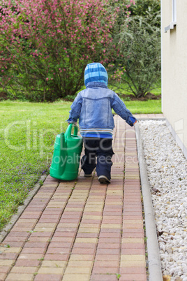 child with watering can in the garden