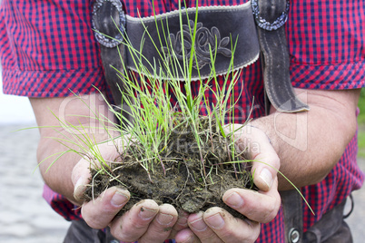 man holding grass with earth