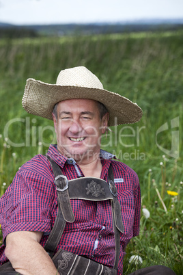 man with straw hat sitting on the spring meadow