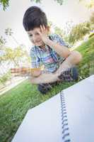 Frustrated Cute Young Boy Holding Pencil Sitting on the Grass