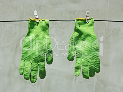 Green gloves hanging on a wire in the sunlight