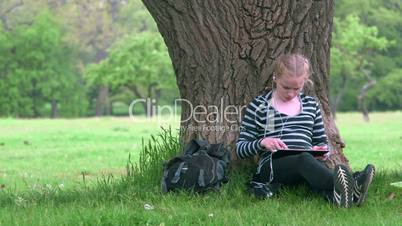 Teenage girl using digital tablet computer in summer park