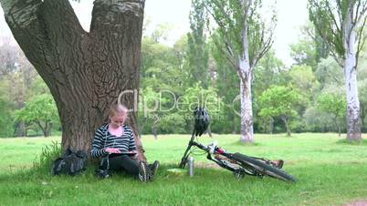 Cyclist girl sitting under tree in the park