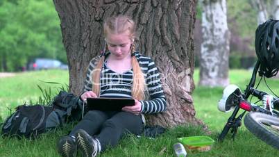 Teenage girl using tablet pc in park