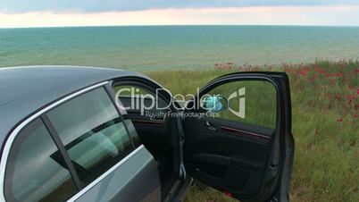 Car is parked with opened door at the seaside