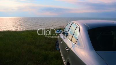 Car parked on the seashore at sunset