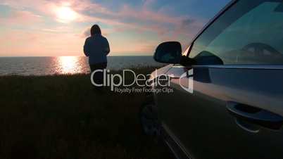 Silhouette of woman near his car at sunset
