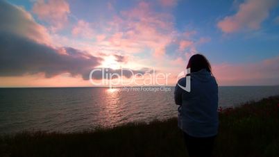 Woman on sea coast watching the sunset