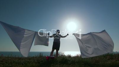 Silhouette of housewife and white laundry on a clothesline