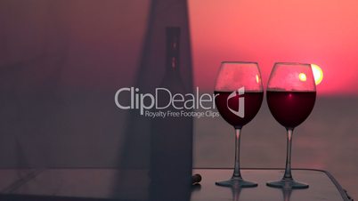 Two red wine glasses at sunset by the sea