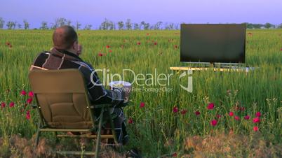 Man watching television in the green field