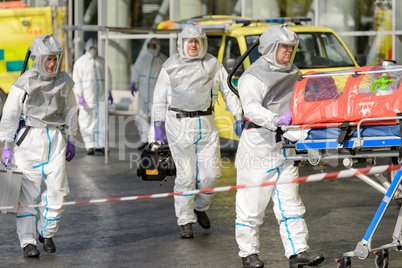 Biohazard team with stretcher walking on street
