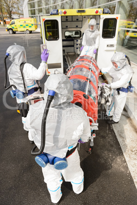 Biohazard team loading stretcher in ambulance