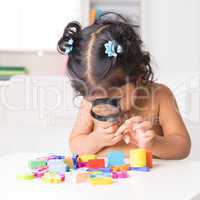 indian girl zoom into toys through a magnifying glass