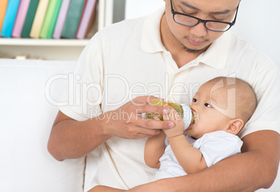 father bottle feeding baby at home.