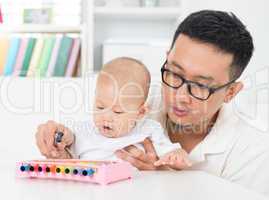 father playing music instrument with baby.