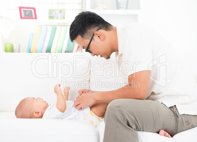 father changing diaper and clothes for baby.
