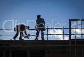 Construction Workers Silhouette on Roof