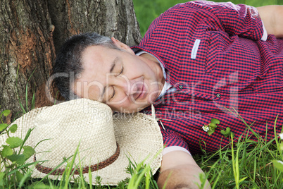 Tired man resting under the tree: