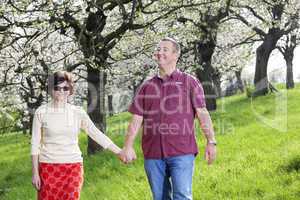 Mature couple runs under blooming cherry trees