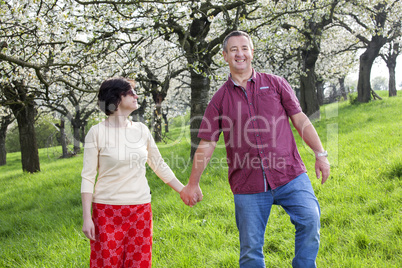 Mature couple runs under blooming cherry trees