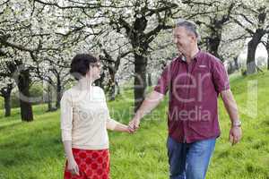 Mature couple runs under blooming cherry trees