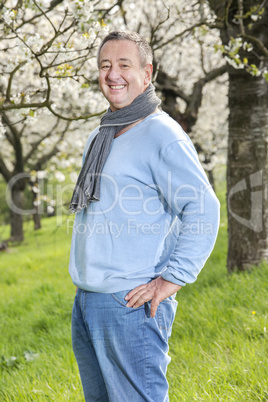 Friendly man in nature under blooming cherry tree