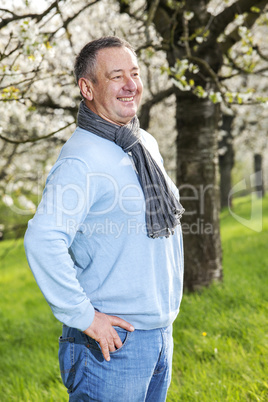 Friendly man in nature under blooming cherry tree