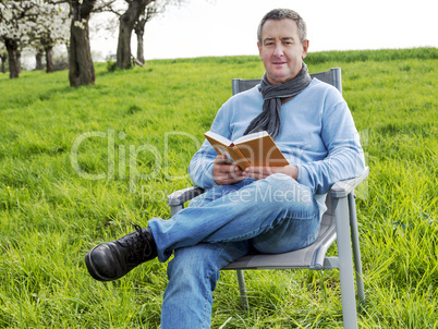 Man reading in the book under blooming cherry tree