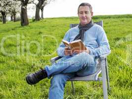 Man reading in the book under blooming cherry tree