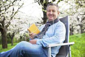 Man reading in the book under blooming cherry tree