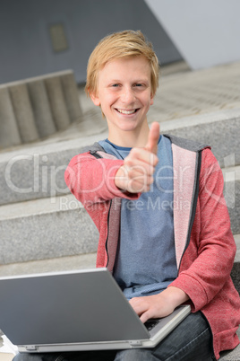 Successful teenage student with laptop thumb-up