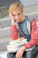 Bored student boy with books and laptop